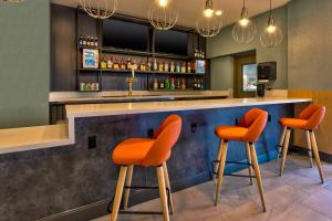 a bar with orange bar stools in a restaurant at Holiday Inn Grand Rapids - South, an IHG Hotel in Cutlerville