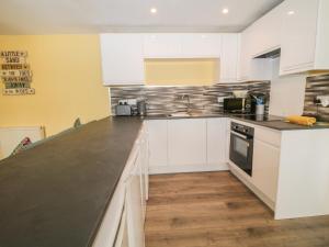 a kitchen with white cabinets and a black counter top at Cherry Tree Cottage in Bude