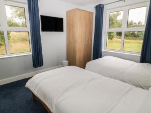 a bedroom with two beds and two windows at Cherry Tree Cottage in Bude