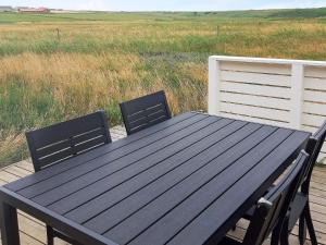 a black picnic table and two chairs on a deck at 5 person holiday home in Lemvig in Lemvig