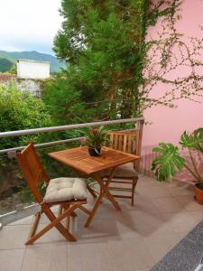 une table en bois et une chaise sur la terrasse dans l'établissement Flamingo Apartment, à Furnas