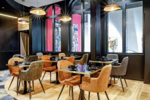 un restaurante con mesas, sillas y ventanas en Leprince Hotel Spa; Best Western Premier Collection en Le Mans