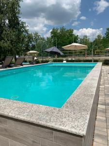 a blue swimming pool with chairs and umbrellas at Mohácsi Wellness Vendégház és Lovasklub in Mohács