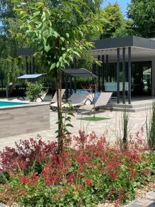 un jardín con un árbol y flores frente a un edificio en Mohácsi Wellness Vendégház és Lovasklub, en Mohács