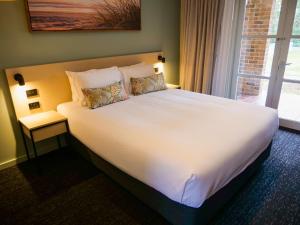 um quarto com uma grande cama branca e uma janela em Nightcap at Hinterland Hotel Nerang em Gold Coast