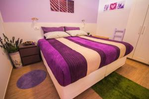 a bedroom with a large bed with a purple comforter at Apartments Lavanda & Cappuccino in Portorož