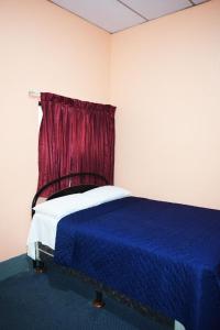 a bedroom with a blue bed with a red curtain at Hotel Asunción in Guatemala