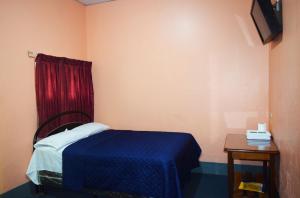 a bedroom with a blue bed and a red curtain at Hotel Asunción in Guatemala