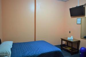 a bedroom with a bed and a table with a tv at Hotel Asunción in Guatemala