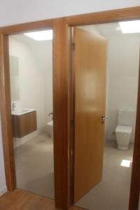 a bathroom with a toilet and a wooden door at Casa das Camélias Garden Guesthouse in Aveiro +20 photos
