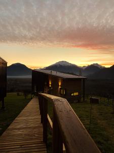 a wooden walkway leading to a cabin with mountains in the background at Alto Pangal Lodge Puerto Aysen in Puerto Aisén
