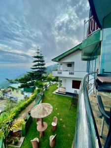 einen Balkon mit einem Regenschirm auf dem Rasen in der Unterkunft Srilak View Holiday Inn in Haputale
