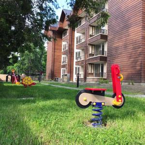 a playground equipment in the grass in front of a building at Pucon oriente Departamento in Pucón