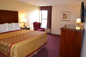 a hotel room with a bed and a chair at Rodeway Inn High Point - Archdale in Archdale +13 photos