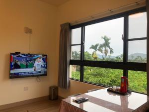 uma sala de estar com televisão e uma grande janela em Longtian Prosperity BnB em Luye