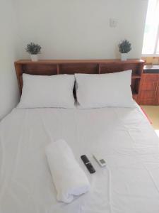 a white bed with two remote controls on it at Guesthouse Berlian Batang Syariah near Kampung Kalisalak Park in Pekalongan