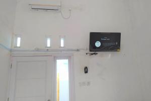 a television on a wall next to a door at Guesthouse Berlian Batang Syariah near Kampung Kalisalak Park in Pekalongan