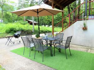 een tafel en stoelen met een parasol op het gras bij White Horse Hotel in Hakuba