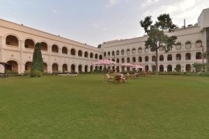 a large green lawn with a red umbrella at The Grand Imperial - Heritage Hotel in Agra