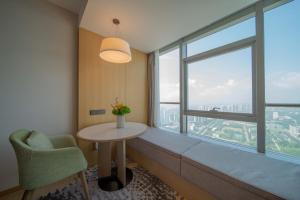 秦皇島市にあるHoliday Inn Qinhuangdao Haigangのテーブルと大きな窓が備わる客室です。