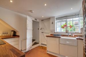 uma cozinha com armários brancos, um lavatório e uma janela em Sweet & cosy 10 Bridewell Cottage with parking available upon request em Bury Saint Edmunds