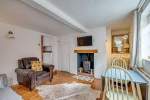 sala de estar con silla de cuero y chimenea en Sweet & cosy 10 Bridewell Cottage with parking available upon request en Bury Saint Edmunds