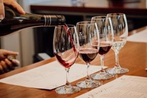 a person pouring wine into a row of wine glasses at Denman Motor Inn in Denman