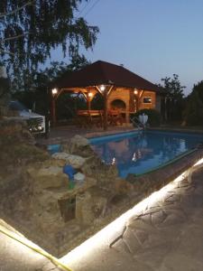 a swimming pool at night with a gazebo at Apartmani Neven in Irig