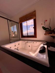 baño con bañera grande y ventana en Brisa de Lavras en Lavras Novas