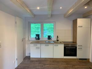 a kitchen with white cabinets and a white refrigerator at Ferienhaus Pfefferminzhütte in Mildenau