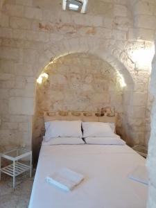 a bedroom with a white bed in a stone wall at Il Casolare nel relax in Ostuni