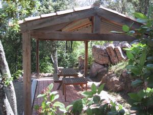 pérgola de madera con mesa de picnic y banco en Locations A Suara, en Porto Vecchio