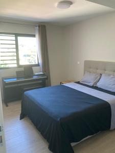 1 dormitorio con cama azul y escritorio en Standing Residence Tevai en Papeete