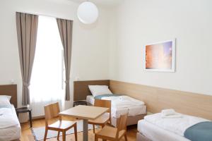 Habitación con 2 camas, mesa y sillas en Domus Peregrini Apartmanok, en Győr