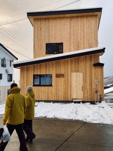 two people walking in front of a small building at Montefino - warm wooden chalet in Nozawa Onsen