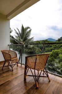 two chairs on a balcony with a view of the jungle at Thenmala Hormuz Inn in Kolattupuzha