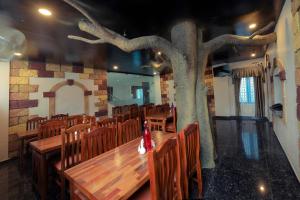 a dining room with a tree in the middle at Thenmala Hormuz Inn in Punalūr