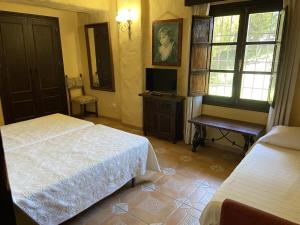 Un dormitorio con dos camas y un escritorio y un televisor. en Cortijo rural Archidona, en Archidona