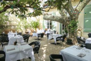 Logis hôtel restaurant de Provence في أورانج: مطعم بطاولات بيضاء وكراسي وشجرة
