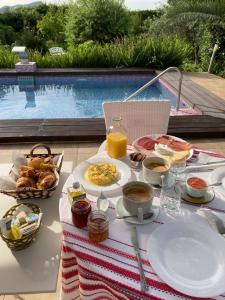 una mesa con desayuno, bebidas y una piscina en Berg & Zon en Gandía