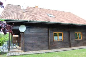 a wooden cabin with a pitched roof with a deck at Holzblockhaus mit Kamin am Kite , Surf und Badestrand in Loissin