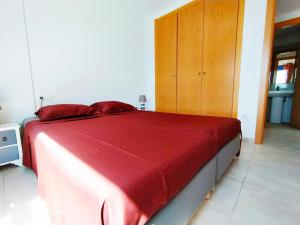 um quarto com uma cama com lençóis vermelhos e um armário de madeira em Blue View em Playa de Gandia