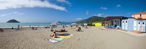 un grupo de personas sentadas en una playa en Residence Riviera, en Albenga