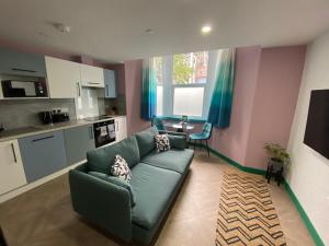 a living room with a green couch and a kitchen at Aaron Wise - 51 Fitzhamon Apartments in Cardiff