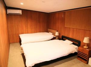 Duas camas num quarto com paredes de madeira em やどバーTATSUJi em Joetsu