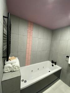 a bathroom with a white tub and a pink wall at Aaron Wise - 51 Fitzhamon Apartments in Cardiff +46 photos