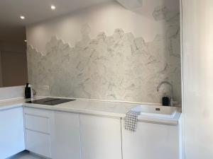a kitchen with white cabinets and a stone wall at Apartamento M Garaje Playa Golf in Zarautz +13 photos