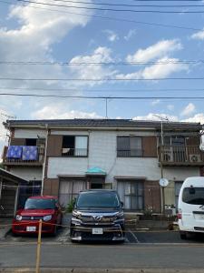 two cars parked in a parking lot in front of a house at メゾン102号 Mason Guest House Suite 102 in Matsudo