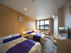 una camera d'albergo con due letti e una TV a schermo piatto di Kichimu a Kamogawa