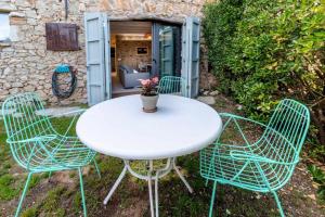 Una mesa blanca y cuatro sillas con una planta. en OCELLS DE MONTGRÍ apartamento rural en el Baix Empordà, en Sobrestany